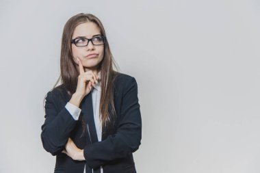 Genç güzel iş kadını çenesi üzerinde eliyle bir şey düşünüyor. Meraklı kız bir arka jant ve mavi kravat ile gözlük giyiyor.