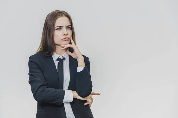 Charmante, mooie zakenvrouw denkt met haar hand op kin. Haar gezichtsuitdrukking is triest. — Stockfoto