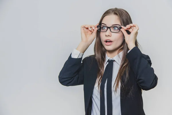 Retrato de cerca de una deslumbrante y asombrada mujer de negocios, que toca el borde negro de las gafas con ambas manos y abre ligeramente la boca . —  Fotos de Stock