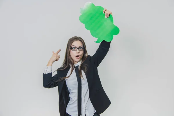 La jeune femme tient une bulle verte sur elle-même, qui est en forme de nuage, avec une main, isolée, sur le fond blanc. Adorable dame regarde la caméra, pointant vers la bulle vocale — Photo