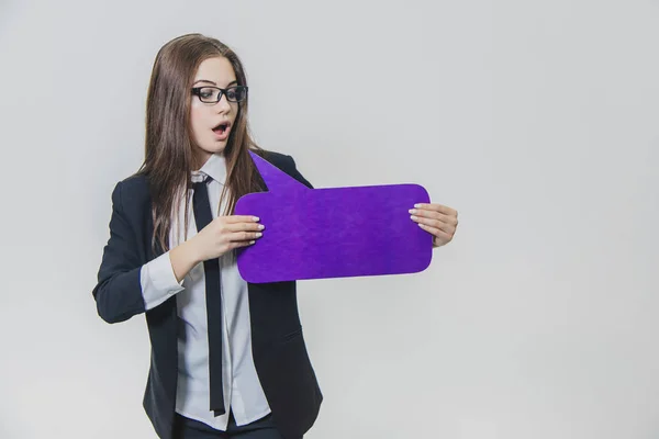 Jonge zakenvrouw houdt een violet speech Bubble closse aan zichzelf, die rechthoekig-gevormd, geïsoleerd, op de witte achtergrond. Jonge dame is op zoek naar en presenteert een violet speech Bubble — Stockfoto