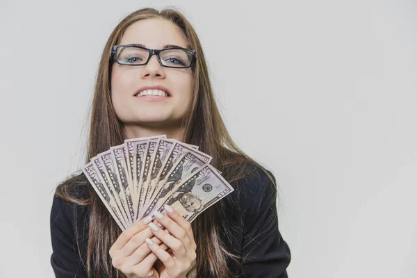 Feliz mujer de negocios emocionado joven está mostrando una pila de dinero, aislado en el fondo blanco. Chica está satisfecho por una gran cantidad de dólares. Adorable mujer de negocios está sonriendo ampliamente usando gafas con —  Fotos de Stock