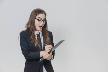 Charming caucasian business woman is holding black paper holder or clipboard and looking at the camera. She came up with an idea and immediately writes it down. clipart