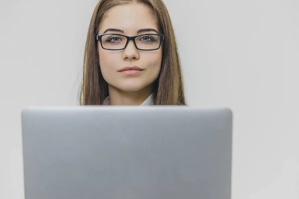 Красивая молодая бизнесвумен носит очки и пользуется современным компьютерным сенсорным экраном. Уверенная женщина-работодатель работает и сконцентрирована. Девушка смотрит на камеру, полную — стоковое фото