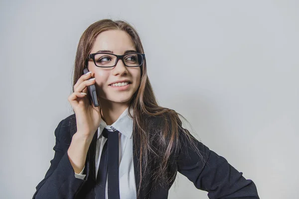 Calm pretty businesswoman is holding a phone in her hand and is talking, looking aside. Thoughtful busy lady. — Stock Photo, Image