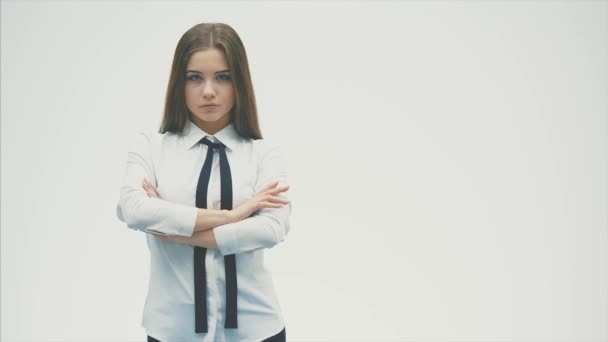 Ung söt affärs flicka som står på en vit bakgrund. Under denna tid han lägger sin hand på armen och tittar på kameran. — Stockvideo