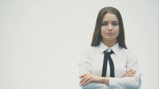 白い背景に立つ若いかわいいビジネスの女の子。この間、フォークフォワードでカメラを見ると、人差し指がまっすぐ表示されます。白いシャツを着て. — ストック動画