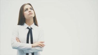 Beyaz bir arka plan üzerinde duran genç güzel kız. Bu düşünce sırasında o çene üzerinde eliyle yukarı bakar.