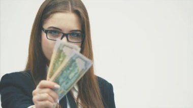 Beyaz bir arka planda duran genç iş kızı. Aynı zamanda bir paket dolar tutar ve kamera içine bakıyor.