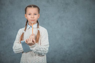 Akıllı bir görünüm ile zeki bir öğrenci, kalem ile el yükseltir gri arka planda izole edilir