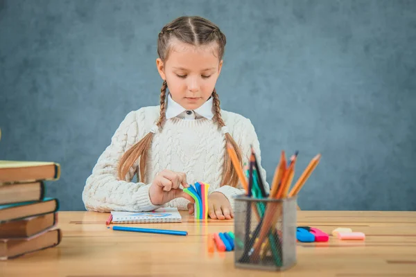 Schoolgirl is sitting at a desk counting colorful stickers. — Stock Photo, Image