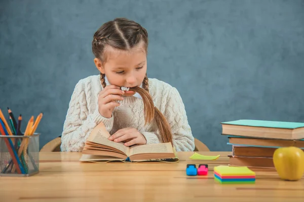 Bella e carina ragazza è coinvolta nella lettura. Non ha tempo di mangiare mela, avendo il cervello in bocca sorpreso, perché c'è una storia interessante scritta nel libro. . — Foto Stock