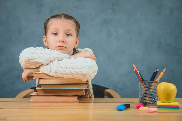 Милая блондинка школьница лежит книги, учебники, стоя на столе возле зеленого яблока и красочные карандаши . — стоковое фото