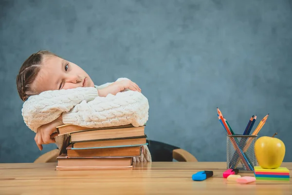 La studentessa assonnata non vuole studiare, ma il sonno e 'la sua priorita'. La ragazza sta aprendo un occhio disteso su un mucchio di libri — Foto Stock
