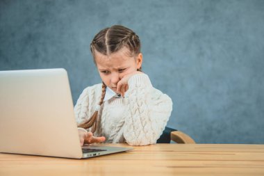 Ciddi genç liseli üzüntü bir tutam ile dizüstü ekran bakıyor. Kız okuyor sıkılıyor.