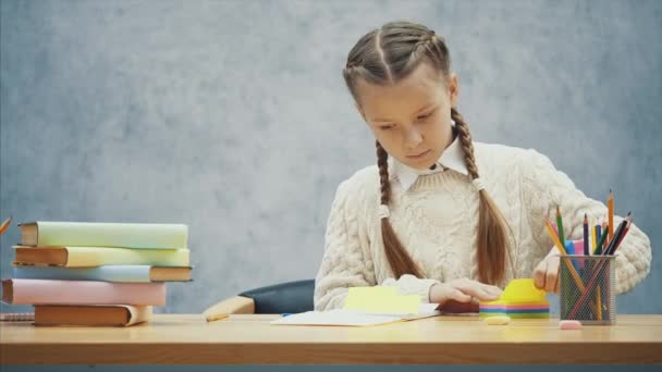 Menina concentrada está colando adesivos coloridos em seu caderno de esboços . — Vídeo de Stock