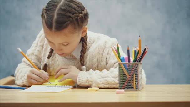 Bonita colegiala se concentra en escribir en pegatinas amarillas . — Vídeos de Stock