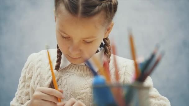 Nice girl with plaits holding yellow pencil and deciding what to draw. — Stock Video