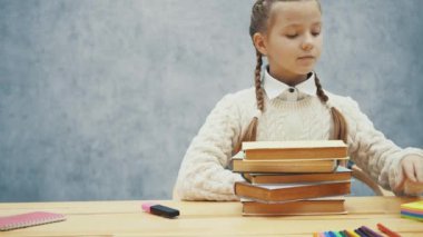 Uykulu küçük kız kitap yığını üzerinde ellerini katlanmış.