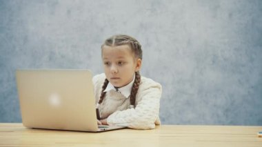 Güzel örgülü ve meraklı yüz exspression ile güzel öğrenci laptop ile masada oturuyor.