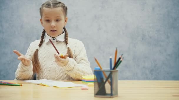 Hübsche Schulkind fällt es schwer, ihren braunen Bleistift zu spitzen. — Stockvideo