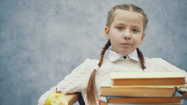 작은 여학생은 상사처럼 앉아 사과를 먹고있다. — 비디오