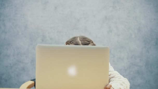 Estudante bonito se esconde atrás do laptop, então de repente apareceu com o rosto sorridente . — Vídeo de Stock