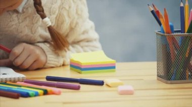 Schoolgirl çevrili wirh sanat malzemeleri çizim konsantre.