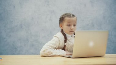 Onu dizüstü bilgisayar ile çalışan ve masasında oturan uzun sarışın saçlı küçük kız.