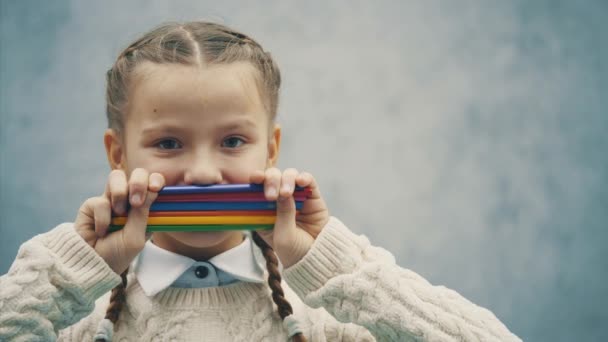 Nyfiken Schoolgirl gömmer munnen bakom en bunt nya överstrykningspennor. — Stockvideo