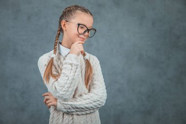 Şık gözlüklü akıllı ve gülümseyen bir okul kızı kendinden emin görünüyor ve gri arka planlar üzerinde izole.