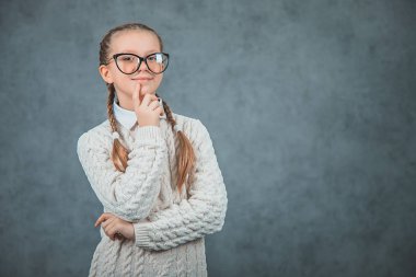 Şık gözlüklü akıllı ve gülümseyen bir okul kızı kendinden emin görünüyor ve gri arka planlar üzerinde izole.