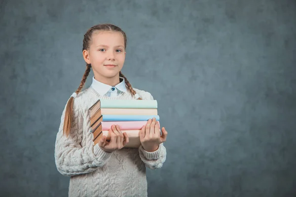 Retrato de close-up de uma menina inteligente abraçando seus livros, isolado em fundos cinzentos . — Fotografia de Stock
