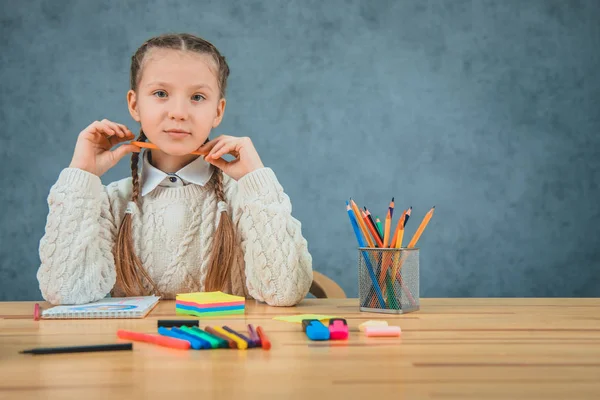 Schöne schöne Schülerin schaut mit konzentrierten Augen und hält Wachsmalstift in ihren Händen unter dem Kinn. — Stockfoto