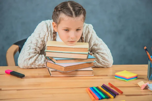 Pequeña estudiante rubia chica de la escuela está apilado con libros . — Foto de Stock