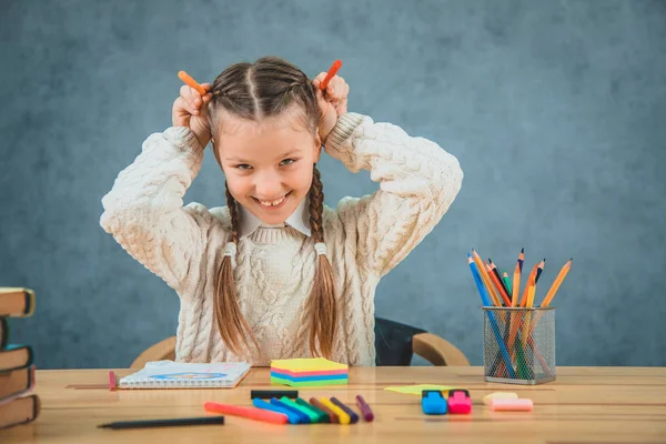 Маленькая школьница широко улыбается и смеется цветными карандашами. . — стоковое фото