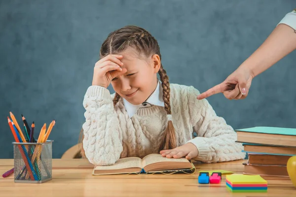 Un maestro estricto y un pequeño estudiante, que se niega a leer. Niña va a llorar en un escritorio en el aula — Foto de Stock