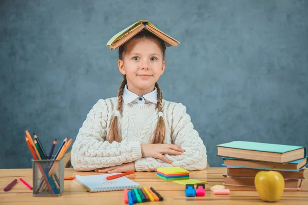 Schoolgirl is with a book on her head watching surprisingly. Good student and a quick learner is ready to study. — Stock Photo, Image