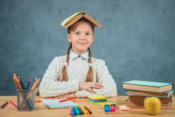 Schoolgirl is with a book on her head watching surprisingly. Good student and a quick learner is ready to study. — Stock Photo, Image