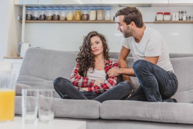 Genç çift kendilerini zevk ve oturma odasında kanepede tv izlerken geri görünümü. Genç adam ve kadın rahatlatıcı ve yeni düz kırmızı şarap içme.