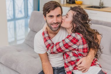 Genç çift evlerinde dinlenirken, kanepede oturarak, Tv. Lovers ve mutlu sarılmak izliyor. Yanağından öpücük.