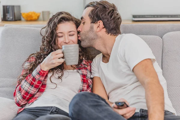 Amor verdadero. Alegre pareja romántica sentada en el sofá en una acogedora habitación y sonriendo . —  Fotos de Stock