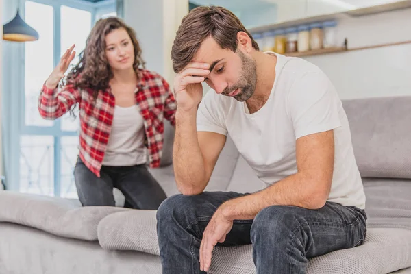 Stel argumenteren. De vrouw schreeuteerde naar haar wanhopige man, zittend op de Bank in de woonkamer thuis. Een man kijkt niet naar zijn vrouw. — Stockfoto