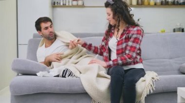 Soğuk battaniye sosisli bir kanepede oturan bir adam. Sıcaklık kontrol. Karısı onun yanında oturuyor ve yardımcı olur. Adam evde. Hasta genç odasında gri kanepe adam. Mutsuz adam. Kavramı