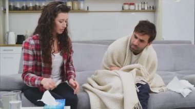 Soğuk battaniye sosisli bir kanepede oturan bir adam. Sıcaklık kontrol. Karısı onun yanında oturuyor ve yardımcı olur. Adam evde. Hasta genç odasında gri kanepe adam. Mutsuz adam. Kavramı