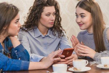 En iyi üç arkadaş kahve içmeye ve dedikodu yapmaya geldi. Kızlar eğlenceli ve güler. Güzel siyah saçlı kızlar.