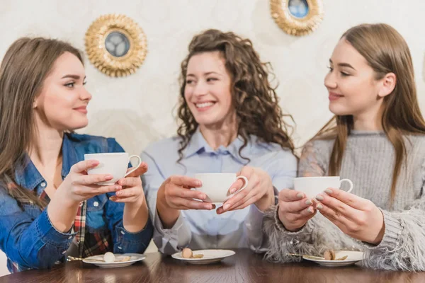 Three women friends enjoy coffee in the cafe. Enjoy coffee while chatting in the cafe. Young and beautiful girls with long blackheads. — Stock Photo, Image