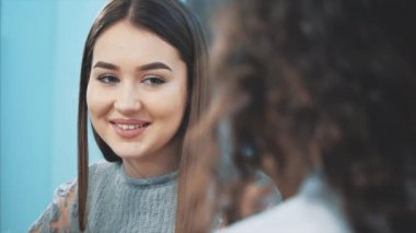 Genç sevimli iyi kız arkadaşlar, bir kafede bir araya geldi. Güzel genç kızlar gülümseyerek, kafeler masada birlikte oturarak geçirilen zamanın tadını çıkarıyorlar.