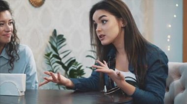 Bir kafede oturan üç sevimli güzel kız. Bu esnada, sohbet ederler ve doğrudan göz de görürler. Güzel siyah uzun saçları var.