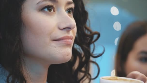 Молодая красивая девушка сидит в кафе. В это время это ложка капучино. Наслаждаясь приятным вкусом кофе и спокойствием . — стоковое видео